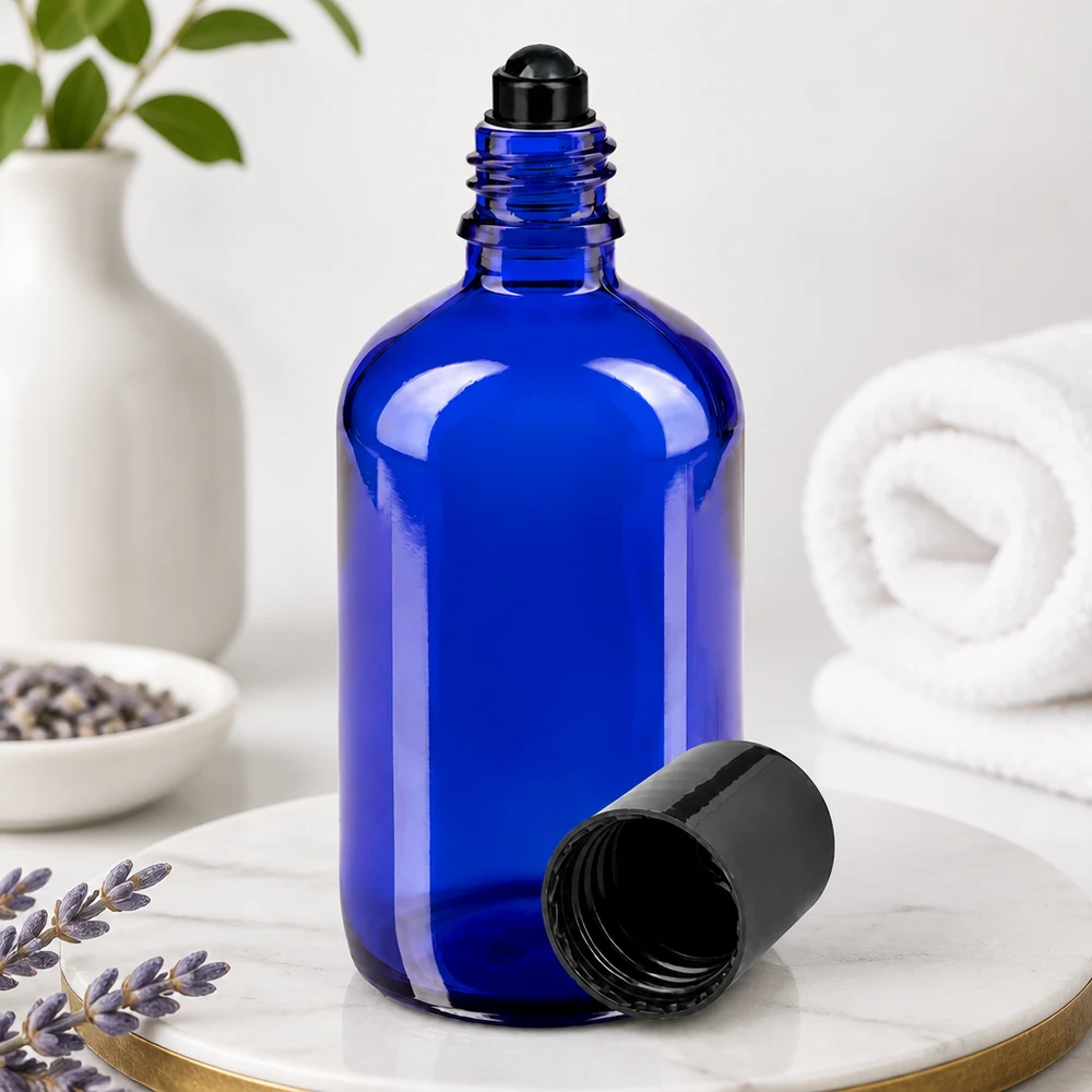 Flacone per deodorante stick in vetro blu 100 ml, roll-on vuoto Flacone di vetro blu da 100 ml con sfera rotante nera e tappo rimosso, appoggiato su una base di marmo