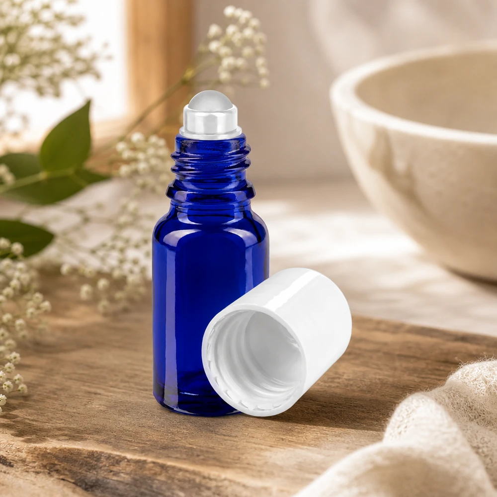Flacone di vetro roll-on da 10 ml, di colore blu cobalto, aperto, con il tappo bianco rimosso, su fondo di legno