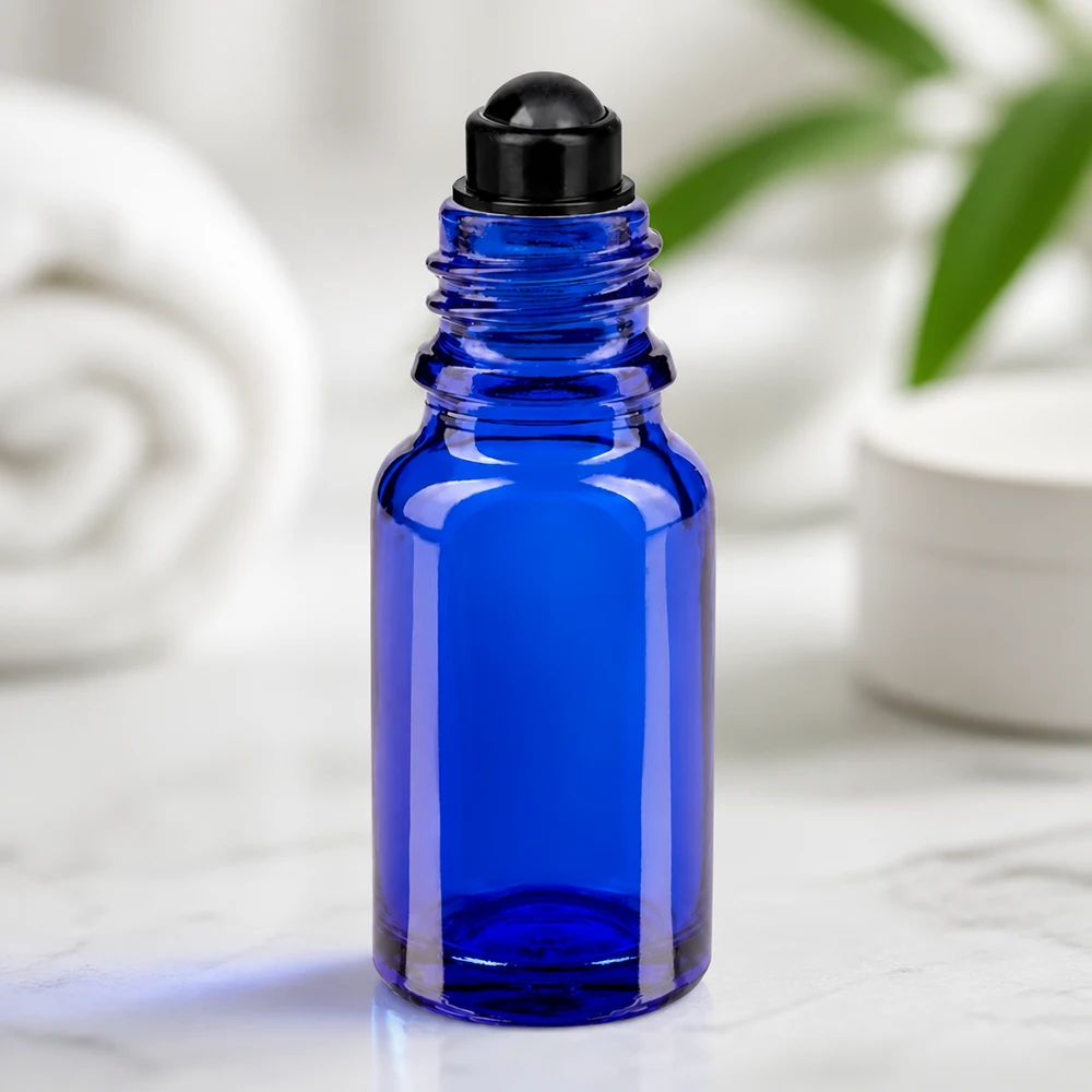 Flacone di vetro blu da 10 ml con applicatore roll-on nero su marmo, su sfondo bianco