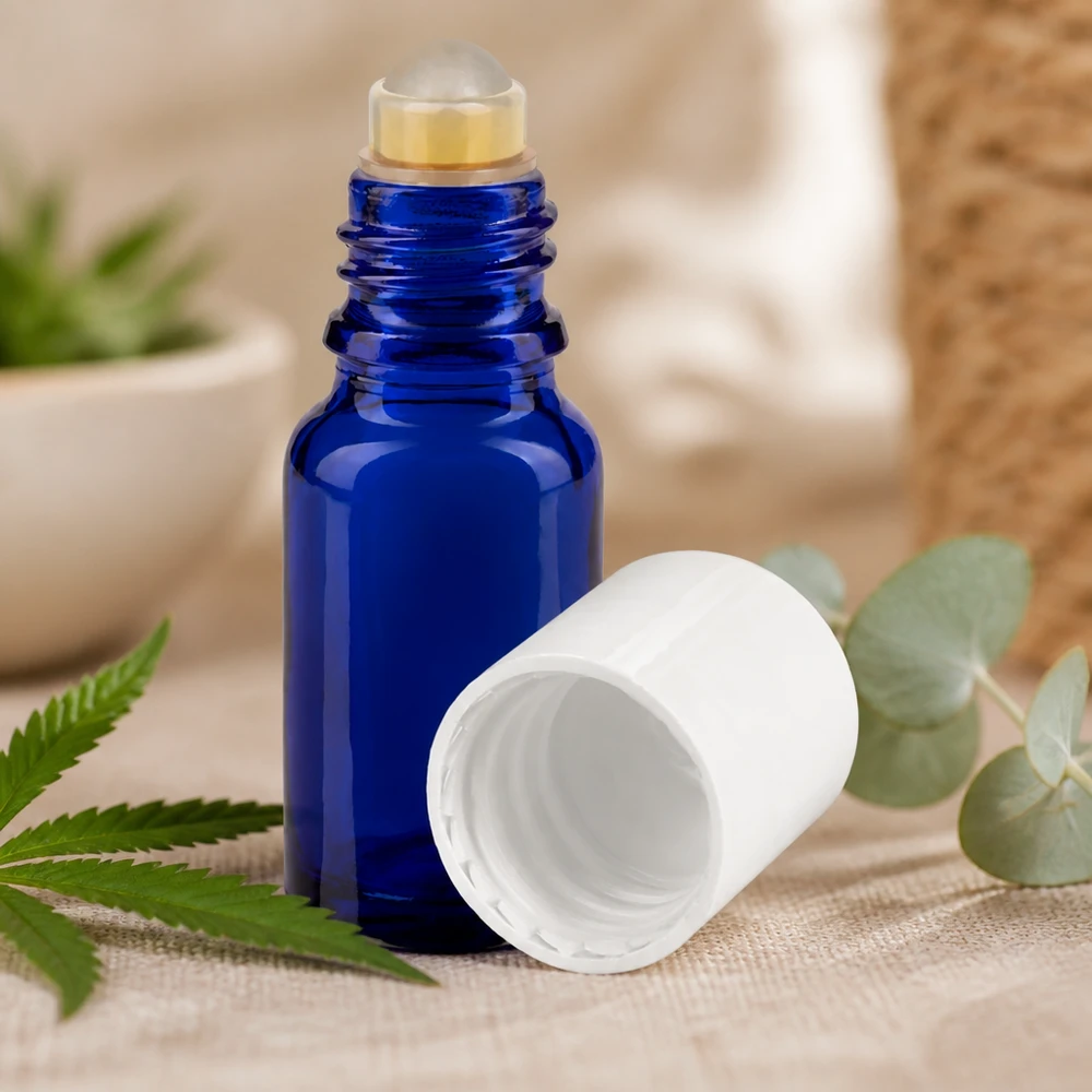 Flacone per deodorante stick in vetro blu 10 ml, roll-on vuoto Flacone roll-on blu da 10 ml con tappo bianco accanto a foglie di canapa ed eucalipto su tessuto di lino