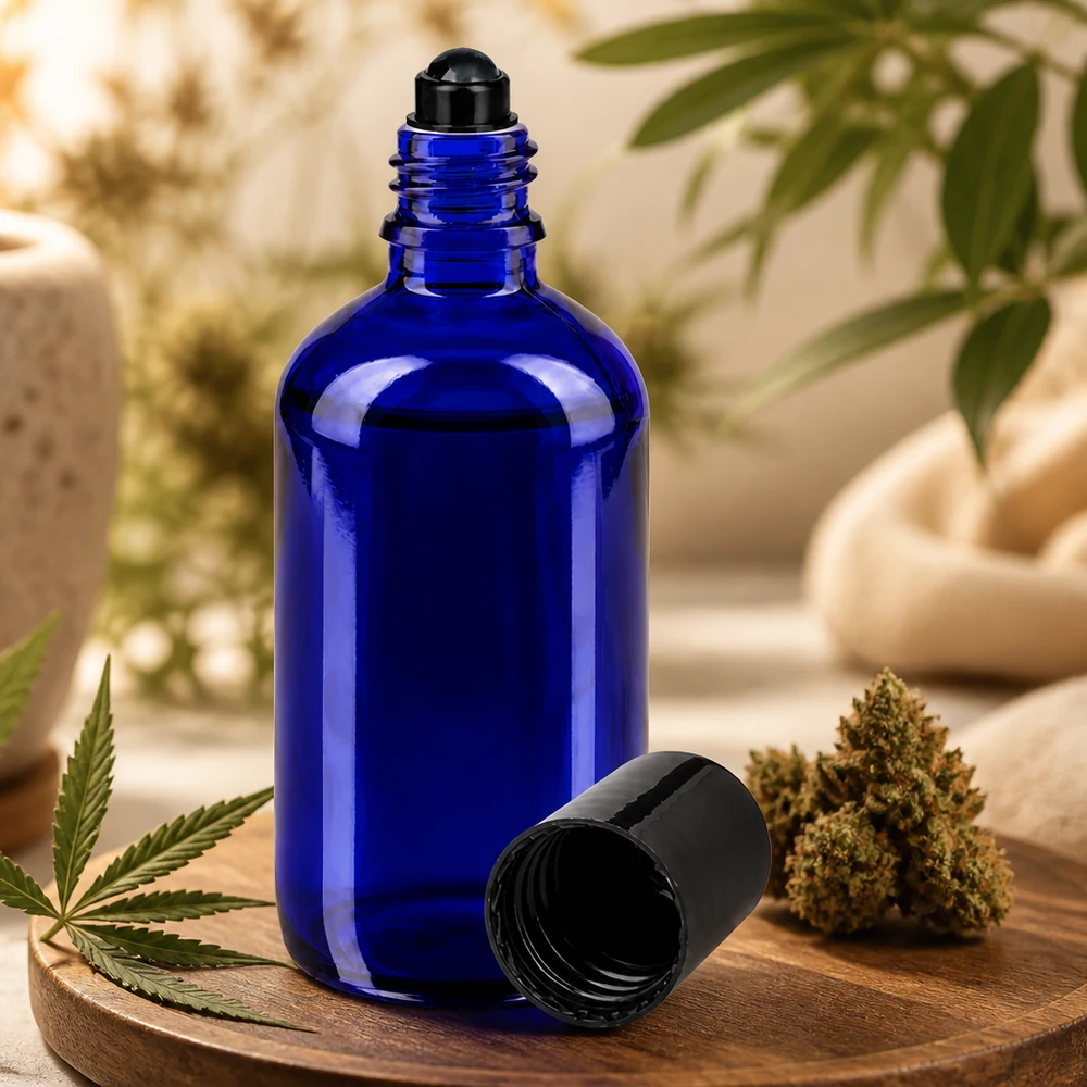 Flacone per deodorante stick in vetro blu 100 ml, roll-on vuoto Flacone roll-on blu da 100 ml in vetro da farmacia accanto a un fiore di cannabis e a una foglia di canapa su un tagliere di legno