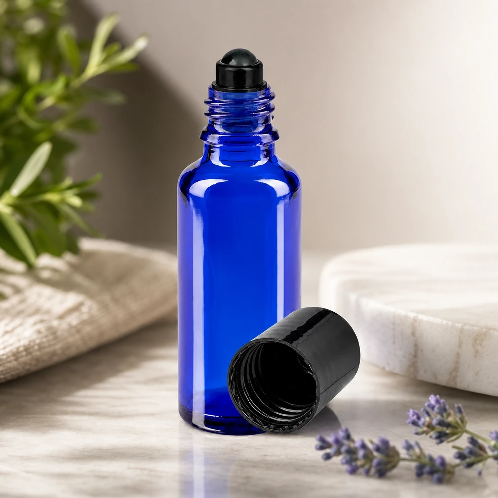 Flacone per deodorante stick in vetro blu 30 ml, roll-on vuoto Flacone di vetro roll-on da 30 ml color blu cobalto con tappo nero, accanto a un rametto di lavanda e uno di rosmarino