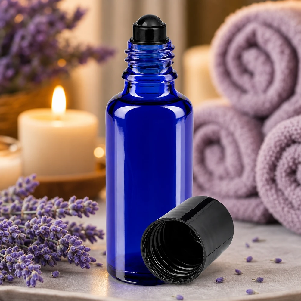Flacone per deodorante stick in vetro blu 30 ml, roll-on vuoto Flacone roll-on da 30 ml in vetro da farmacia di colore blu cobalto con tappo nero, accanto a fiori di lavanda e candele