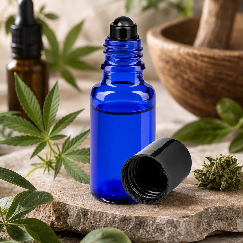 Piccolo flacone roll-on da 20 ml in vetro da farmacia blu accanto a una pianta di cannabis e a un mortaio