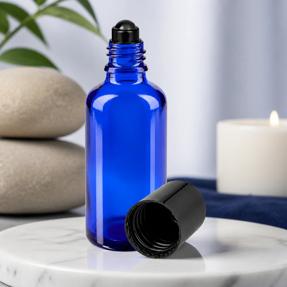 Flacone di vetro blu da 50 ml con applicatore roll-on nero e tappo rimosso su fondo di marmo