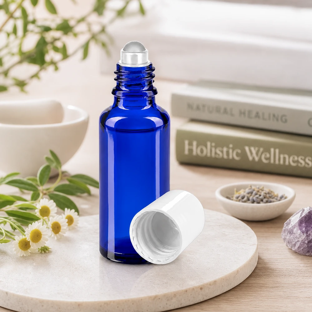 Flacone roll-on cilindrico da 30 ml in blu cobalto con tappo bianco, accanto a erbe medicinali e ametista