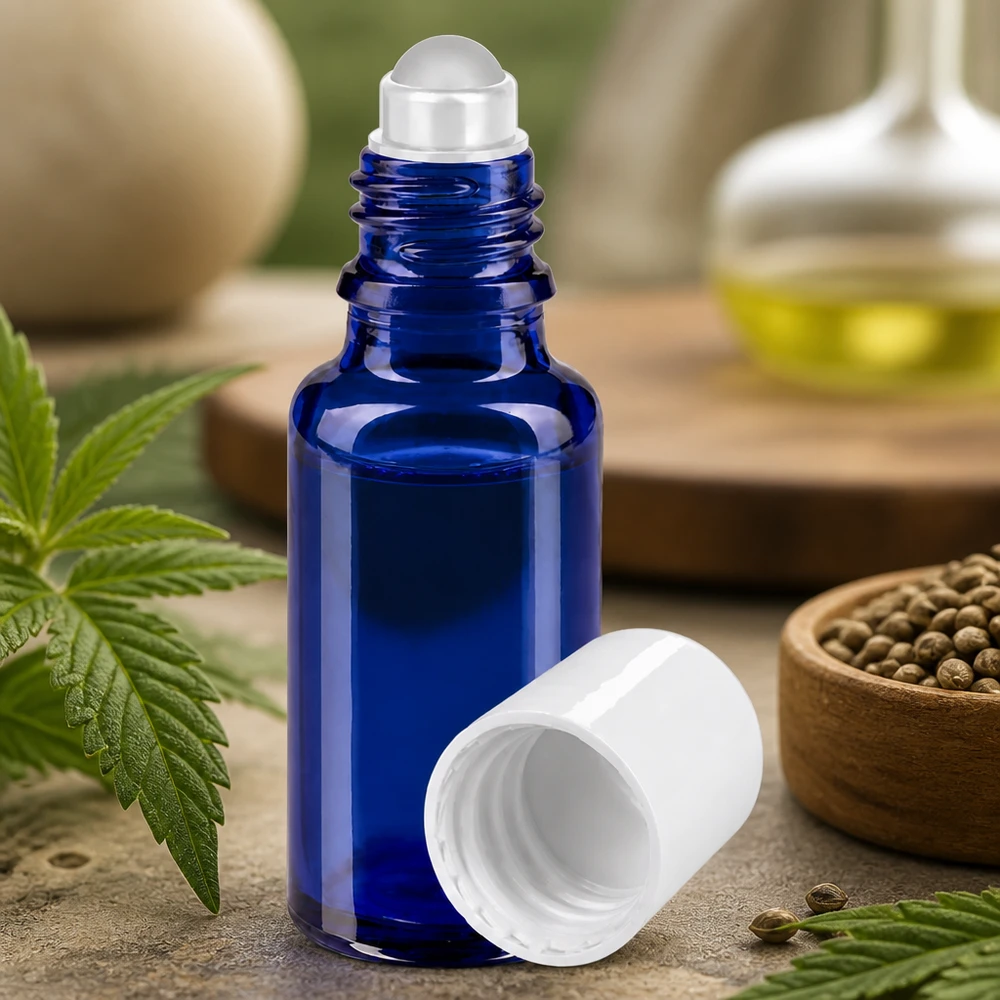 Flacone per deodorante stick in vetro blu 20 ml, roll-on vuoto Flacone di vetro blu da 20 ml con applicatore a sfera e tappo bianco, circondato da foglie e semi di canapa