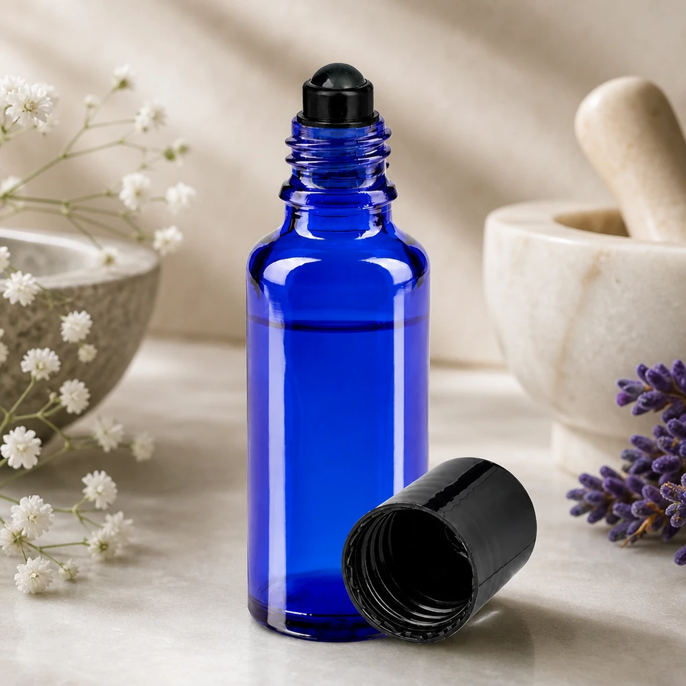 Flacone roll-on da 30 ml blu da farmacia con sferetta nera, accanto a una lavanda e a un mortaio